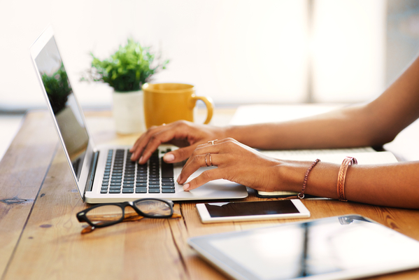 A person sitting at their desk and typing on their laptop.