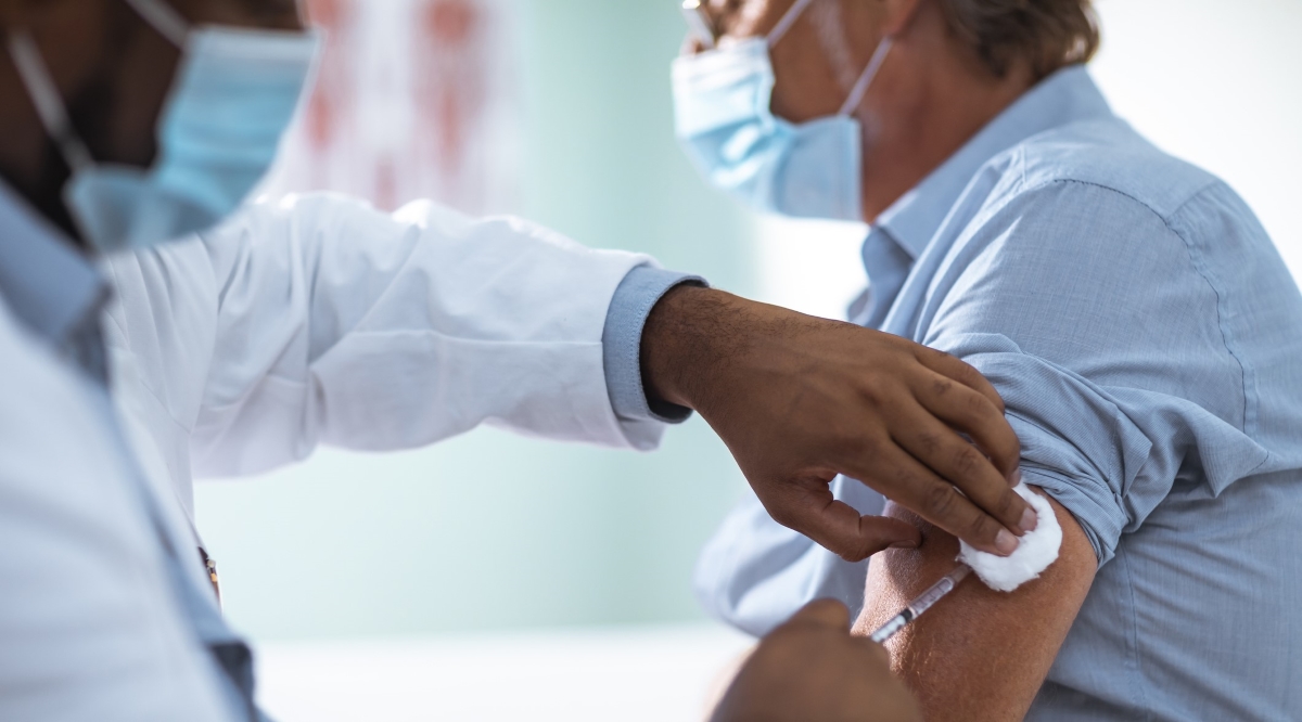 Close up of a mature man taking a vaccine in his doctors office.