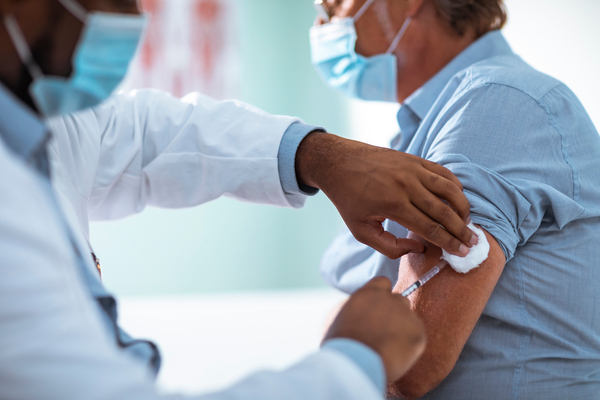 Close up of a mature man taking a vaccine in his doctors office