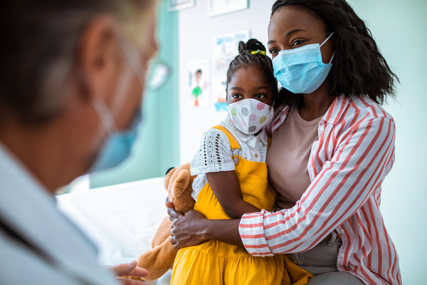 Masked parent and masked child make a visit to the doctor.