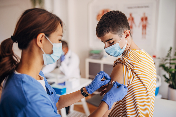 Nurse putting band aid on patient's arm after covid-19 vaccination