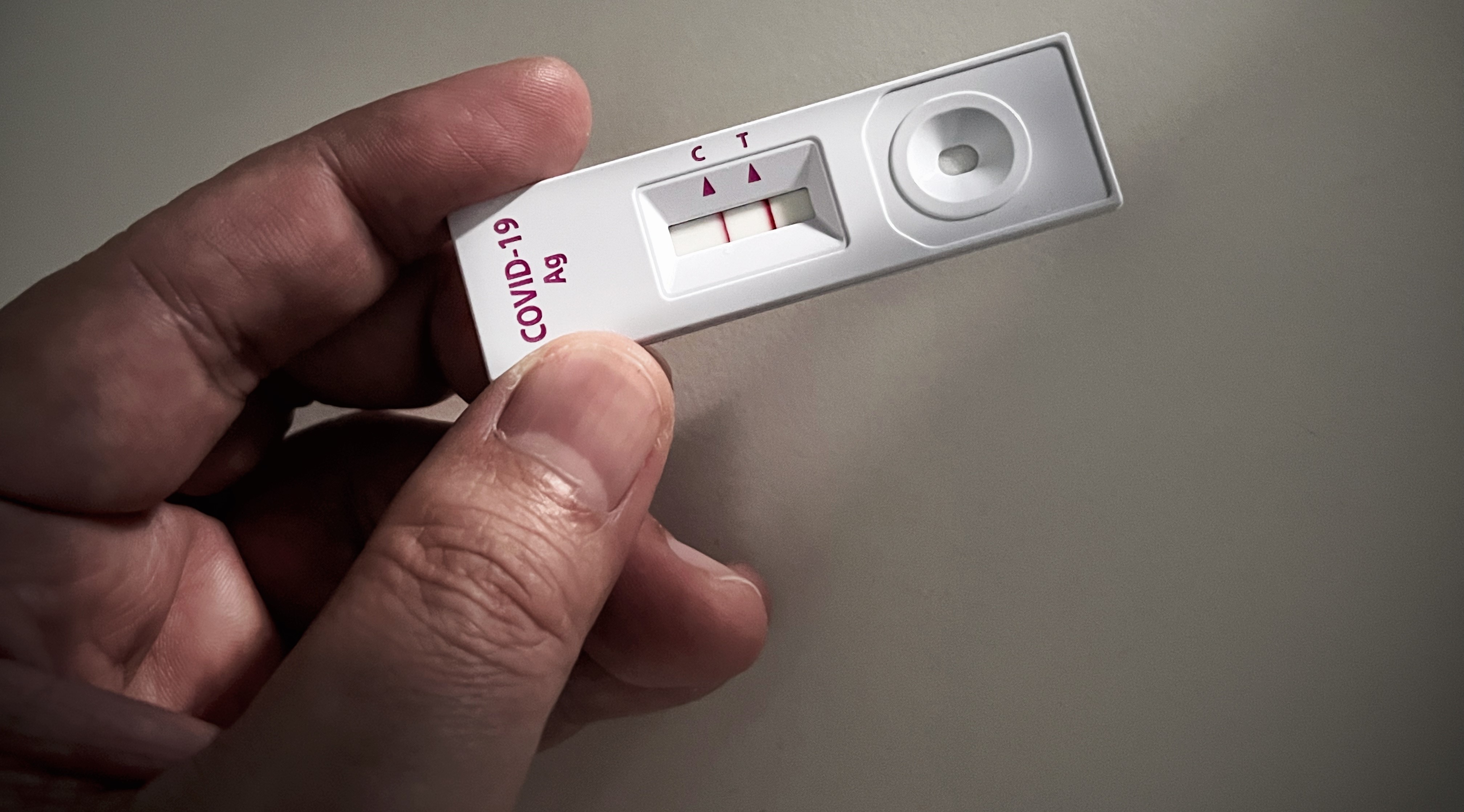 Close-up of adult hand holding a positive COVID-19 or SARS CoV-2 test