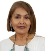 Mae-Gilene Begay smiles in her headshot with a white top and embellished necklace.