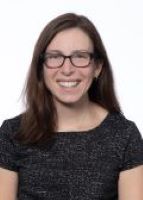 Jennifer Schuster poses for a headshot in reading glasses and short sleeve black top.