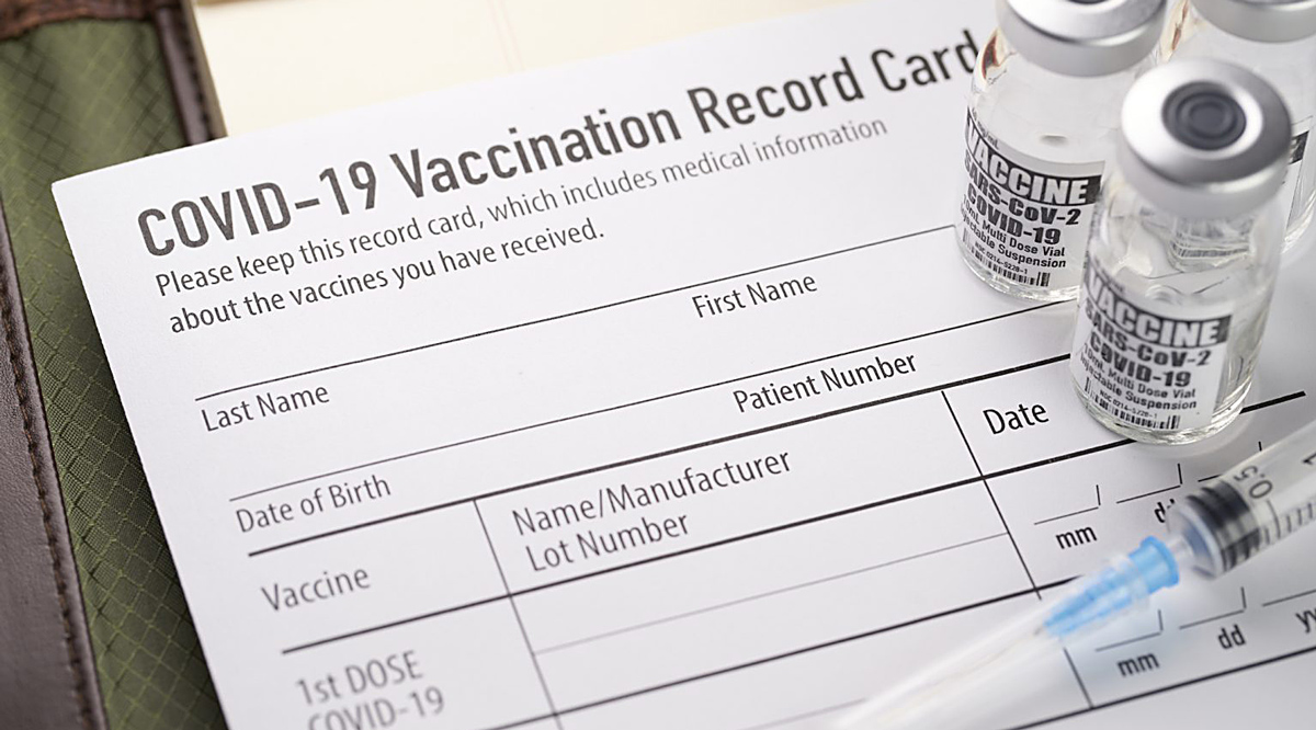 Covid-19 vaccination record card with vials and syringe.