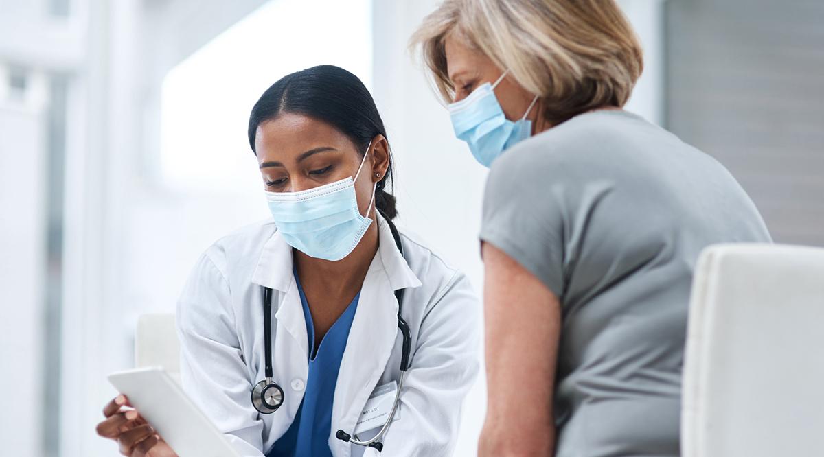 A young doctor using a digital tablet during a consultation with a senior woman