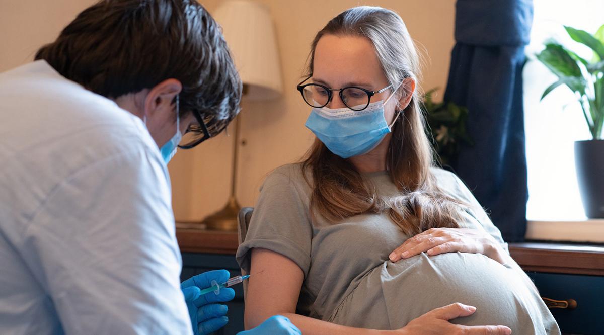 Doctor/nurse giving vaccine injection to pregnant woman