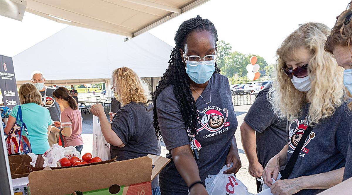 A diverse group of people wearing masks and buying items from a vendor. 