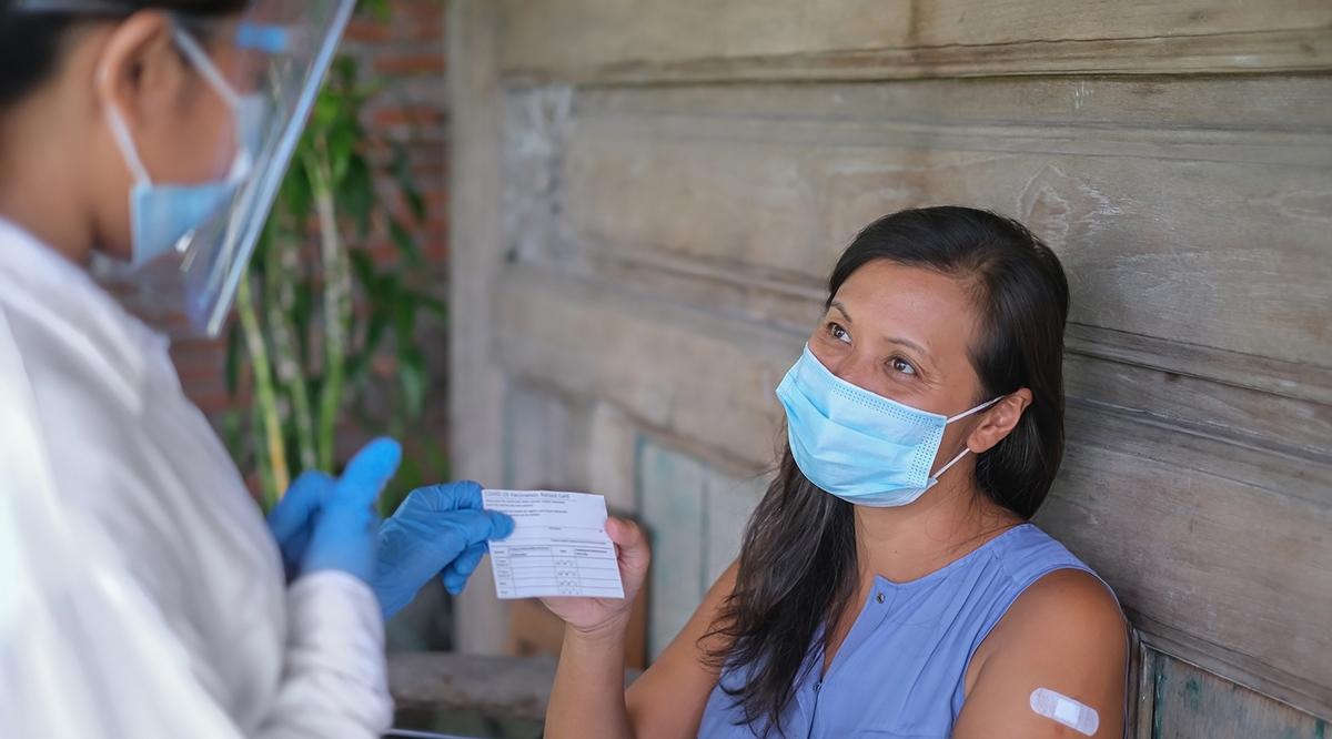 Vietnamese woman receiving a COVID-19 vaccination card