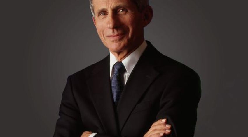 Anthony Fauci, MD poses in a black suit and blue tie with his arms folded across his chest.
