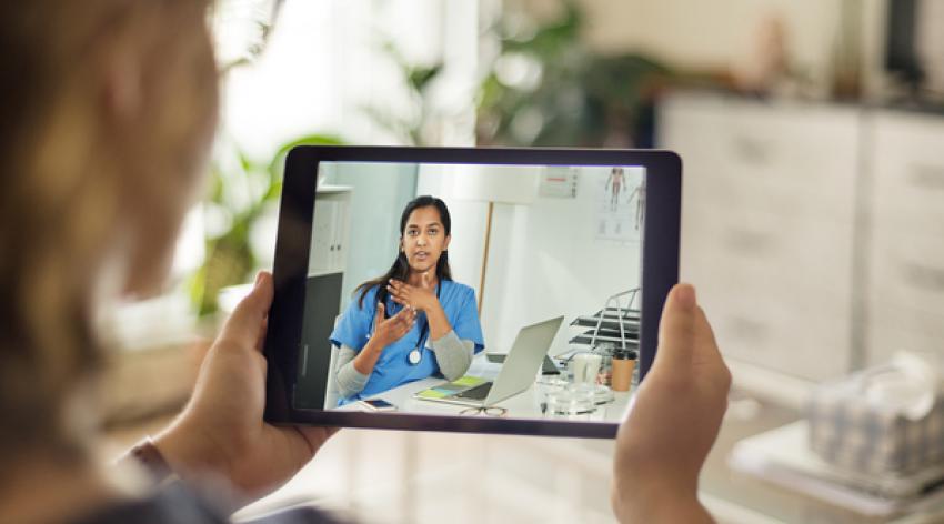 Over the shoulder shot of a patient talking to a doctor using of a digital tablet