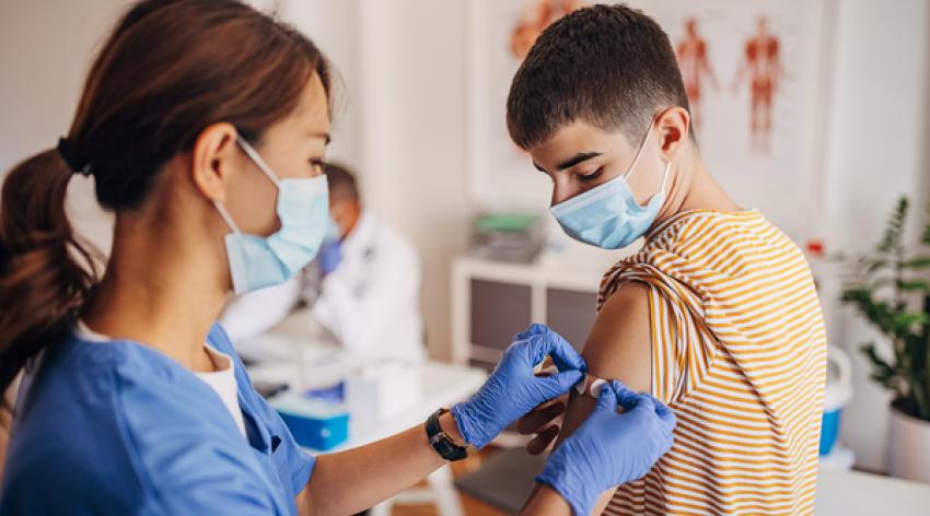 Nurse putting band aid on patient's arm after covid-19 vaccination